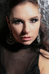 a beautiful, fashionable young brunette of tall stature, on a white background in latex gloves and a black bodysuit, stands in the studio