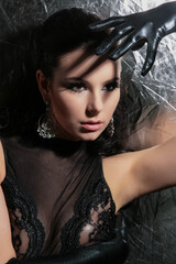 a beautiful, fashionable young brunette of tall stature, on a white background in latex gloves and a black bodysuit, stands in the studio