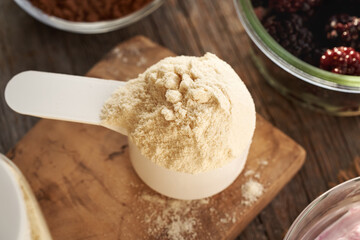 Whey protein powder in a measuring cup, with cranberries in the background