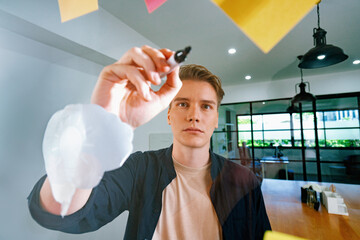 Professional caucasian businessman writing marketing idea by using mind map and sticky notes on glass board at modern meeting room. Creative business and planing concept. Closeup. Immaculate.