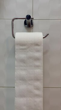 Everyday Routine: A simple yet relatable image of a hand reaching for a roll of toilet paper. The image captures a mundane yet essential moment in everyday life.
