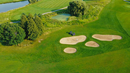 Aerial view of a golf course with sand bunkers and golf cart. A vibrant aerial view of a lush golf...