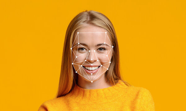 A young woman in a bright orange sweater smiles while facing the camera. Over her face, a digital overlay illustrates facial recognition features, showcasing modern technology.