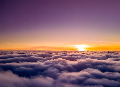 Above the clouds with yellow and violet colors and a setting sun - Powered by Adobe