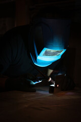 Worker Welding with Blue Mask and Torch in Industrial Setting