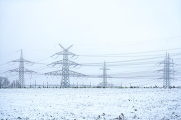 overhead transmission winter electrical energy tower and high voltage lines on the field and nature...