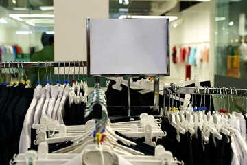 Clothing rack in a modern retail store showcasing empty hangers and promotions
