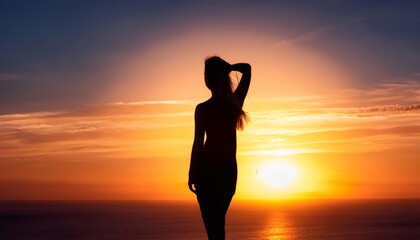 Fototapeta premium Woman silhouetted, caressing hair against vibrant orange sunset seascape