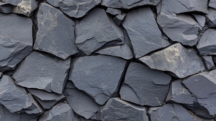 Close up of dark gray stone wall with irregular shapes and rough texture