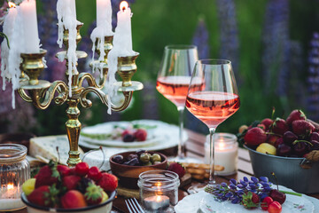 Perfect surprise date for loving couple, private wedding, romantic marriage proposal. Summer, sunset, golden hour. Appetisers. Beautiful elegant outdoor arrangement in meadow with purple blue lupins