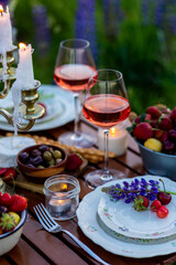 Perfect surprise date for loving couple, private wedding, romantic marriage proposal. Summer, sunset, golden hour. Appetisers. Beautiful elegant outdoor arrangement in meadow with purple blue lupins