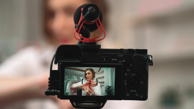 Rear view behide camera screen display influencer shoot live streaming vlog video review makeup prim social media or blog. Girl with cosmetics studio lighting for marketing recording session online.