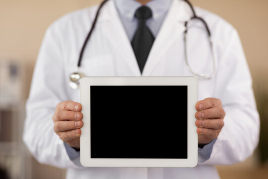 Best App. Adult male doctor holding digital tablet with black blank screen mock up, showing to camera