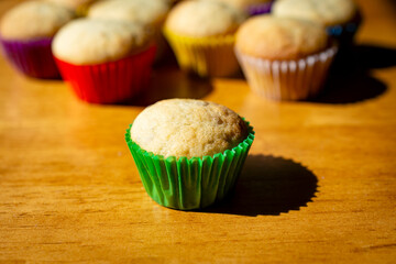 A mini banana muffin upclose with additional muffins in the background.