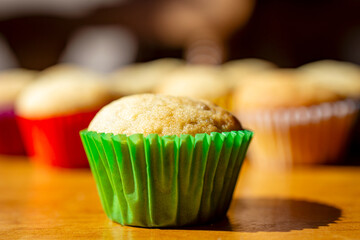 A mini banana muffin upclose with additional muffins in the background.