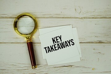 Key Takeaways text message on sticky note with magnifying glass on wooden background
