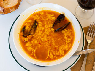 Seafood rice broth served in white plate with serving pieces