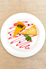 Delicious mango cheesecake with berry sauce garnished with mint