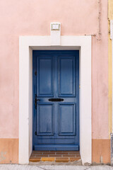 Aigues-Mortes, Gard, Occitania, France. Blue painted door in a pink stucco wall.