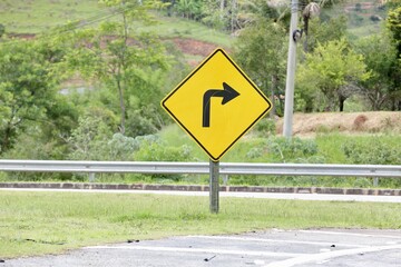Placa de sinalização de transito vire a direita na cor amarela com fundo desfocado de uma casa.