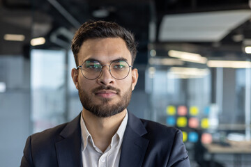 Fototapeta premium Close-up portrait of successful confident businessman, man in business suit looking at camera, financier investor at workplace inside office.