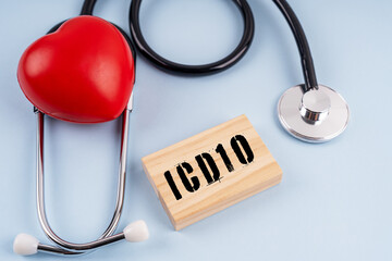 Red heart and stethoscope on blue background with ICD10 text on wooden block.Health care concept.