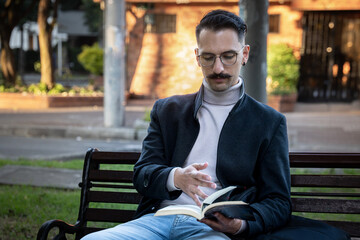 Obraz premium Hispanic man sitting in a park reading a book