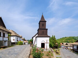 Village high street with church. The Paloc village Holloko in Hungary, listed as UNESCO World Heritage Site. The traditional farm houses form a complete village as it looked during the middle ages.
