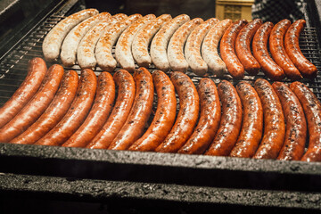 Rows of sizzling sausages, perfectly grilled on a barbecue, with golden-brown crusts and smoky flavors. The scene captures the essence of outdoor cooking, hearty food, and culinary delight.