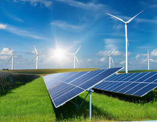 Wind power plant on a green field, sunny summer day, photovoltaic panels in the distance in the background