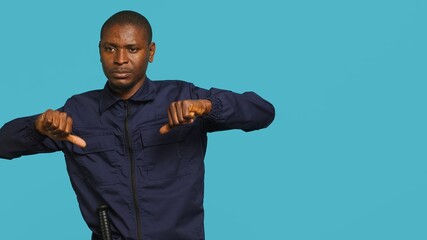 Security guard doing thumbs down sign gesturing, denying public access in restricted area. Portrait...