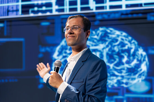 Smiling speaker speaking at tech conference, exploring latest AI technology trends and case studies. Happy IT specialist presenting how artificial intelligence is shaping future during event