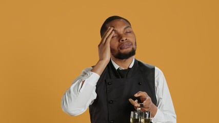 Restaurant employee dealing with a painful headache while he serves clients, carrying a cruet set for excellent customer satisfaction. Unwell waiter in pain with migraine. Camera A.
