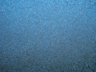 A blue background with a lot of frozen ice on glass texture. The texture is very fine and the color is blue. Cold winter season.