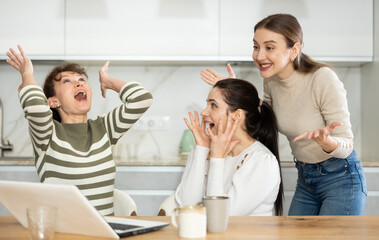 Women are sitting at computer and are immensely happy, exclaim joyfully and are fortunate to receive good news about win