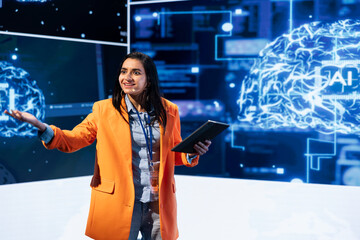 Woman using microphone and tablet to do presentation at workshop exploring developments in AI and...