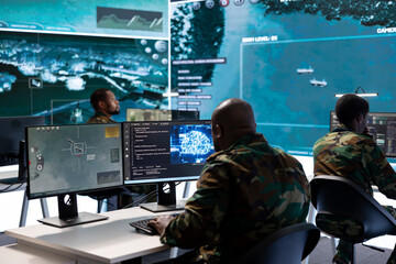 Military specialist in a high tech control center managing satellite radar surveillance, collecting...