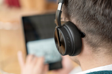 Person wearing headphones while using a tablet for work or leisure in a cozy indoor setting