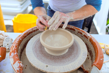 Skilled potter uses hands to refine clay bowl while demonstrating techniques at workshop studio