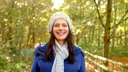 Head and shoulders portrait of smiling mid adult woman wearing hat and scarf walking along path through autumn countryside - shot in slow motion - Powered by Adobe