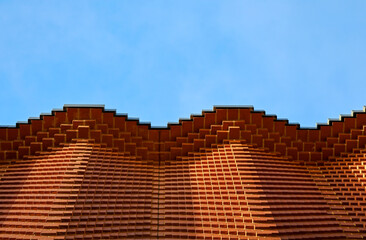 wave patterned brick wall set against a blue sky