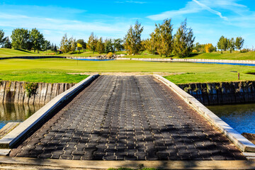 A bridge over a body of water with a golf course in the background