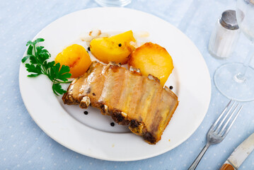 On plate are juicy and fatty fried pork ribs with crust, seasoned with coarse salt and finely chopped herbs