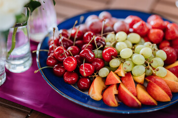 Fresh fruit platter with strawberries, grapes, and peaches on table, perfect for summer events