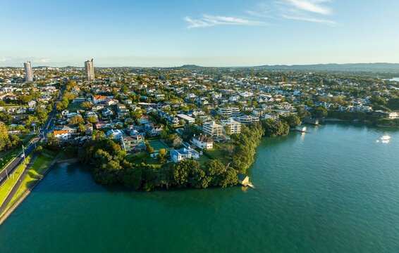 Aerial view of a residential area bordering a waterway. Houses and apartments line the shore, showcasing a mix of architectural styles.  Herne Bay, Auckland, New Zealand