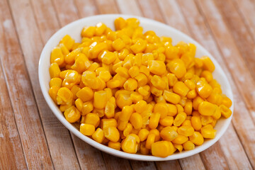 Grains boiled corn on plate on wooden table. Healthy vegetarian ingredient