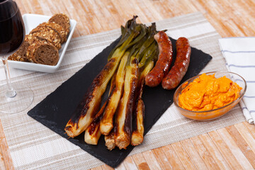 Top view of Catalan grilled calsot with sausage served on plate. Calsot con butifarra