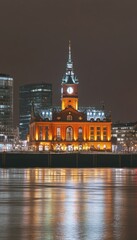 Obraz premium Historic Building with a Clock Tower Beautifully Illuminated at Night in Hamburg. Germany.