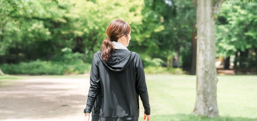 公園を散歩・ウォーキング・ランニングするアジア人女性の後ろ姿
