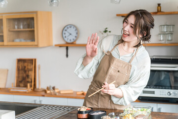 キッチンでお弁当を詰める若いアジア人女性
